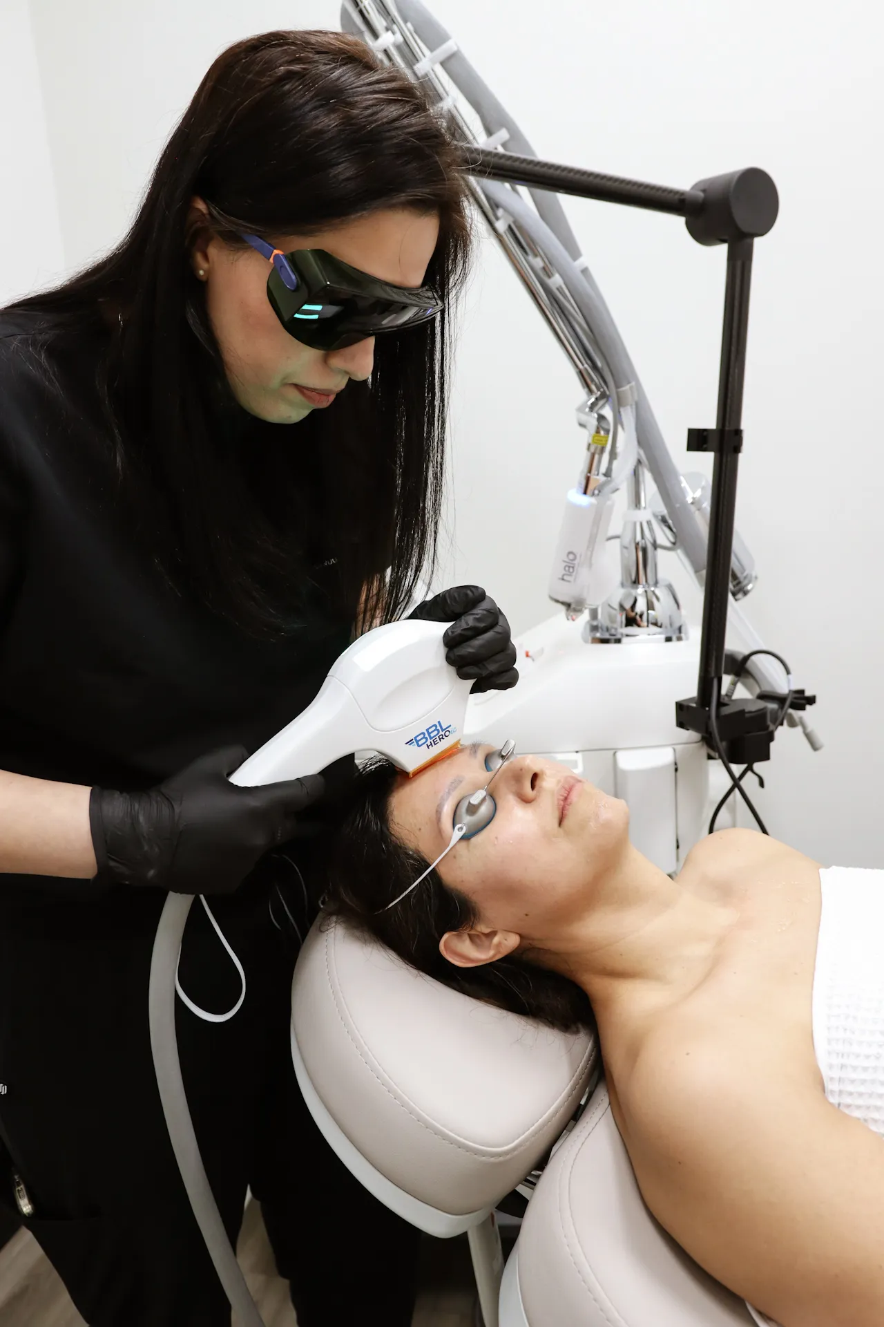 A clinician treats a patient’s brow with the BBL HEROic handpiece, eye shields in place