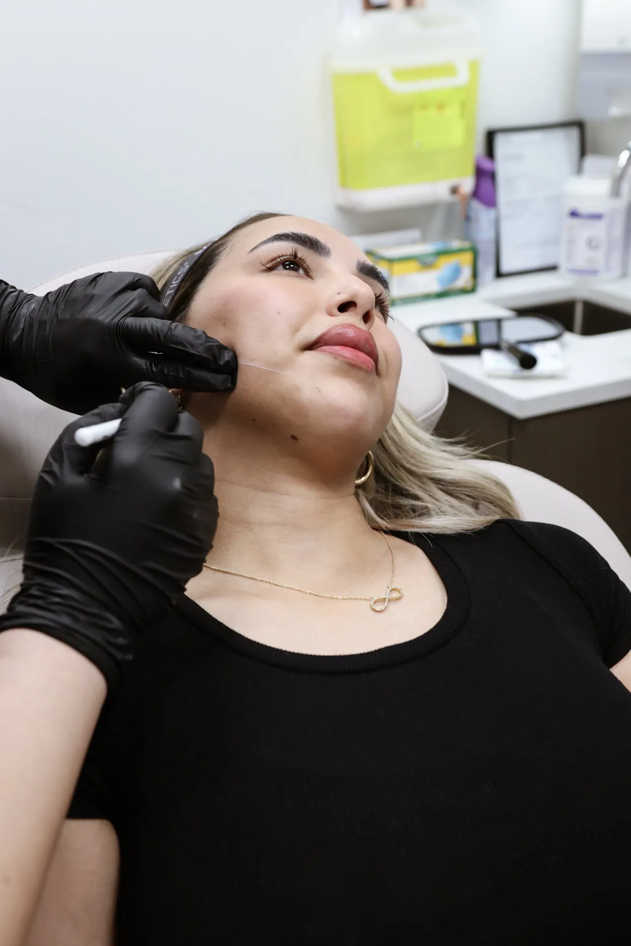 A clinician performs an injection along a patient’s jawline